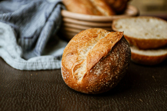 Ein selbstgebackenes Weizenbrötchen mit langer Stockgare auf dem Frühstückstisch