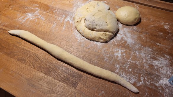 Der weiche Teig für den Hefezopf wird erst rundgeschliffen und dann zu einem dünnen Strang ausgerollt