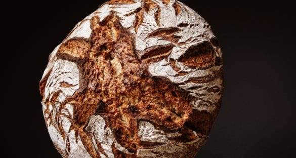 Ein dunkles Bauernbrot auf einem rustikalen Holzhintergrund bereit zum Genießen